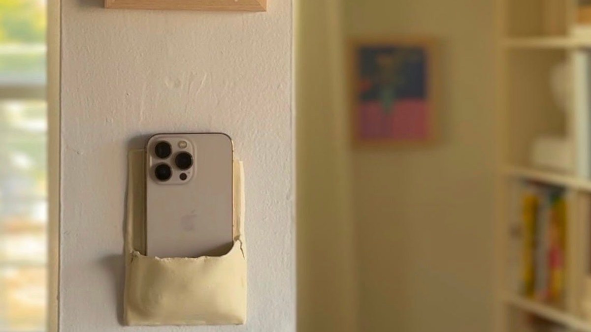 A smartphone tucked into a pocket carved into a wall
